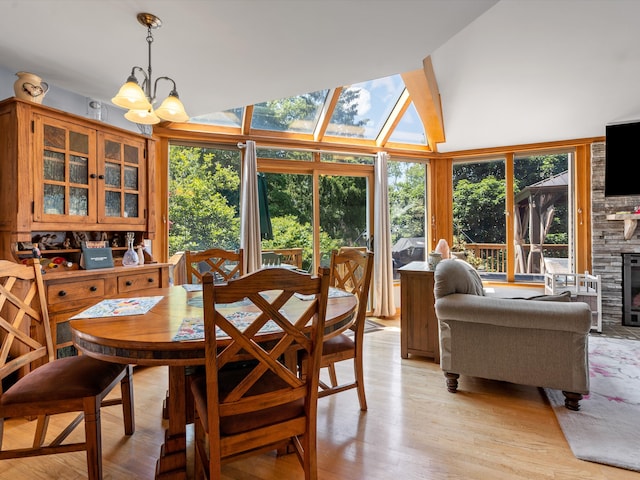 3097 Lansdowne Rd, Waterford, MI 48329 - dining room with light wood-type flooring, a chandelier, high vaulted ceiling, and a stone fireplace