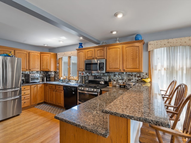 3097 Lansdowne Rd, Waterford, MI 48329 - kitchen with appliances with stainless steel finishes, a peninsula, a sink, tasteful backsplash, and brown cabinetry