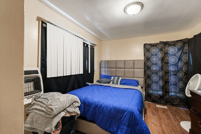 bedroom featuring heating unit and wood finished floors