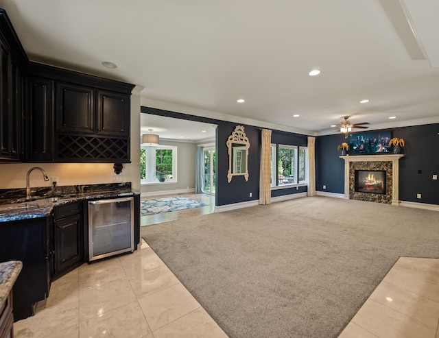 680 Pear Tree Ln, Grosse Pointe Woods, MI 48236 - kitchen featuring crown molding, a sink, dark cabinets, open floor plan, and a warm lit fireplace