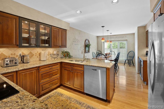 5117 Woodview Ct, Dearborn, MI 48126 - kitchen featuring stainless steel appliances, a sink, a peninsula, pendant lighting, and glass insert cabinets