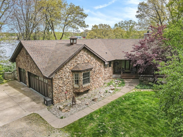 14965 Loon Lake Dr, Bellevue, MI 49021 - view of front of house featuring stone siding, a shingled roof, a chimney, concrete driveway, and an attached garage