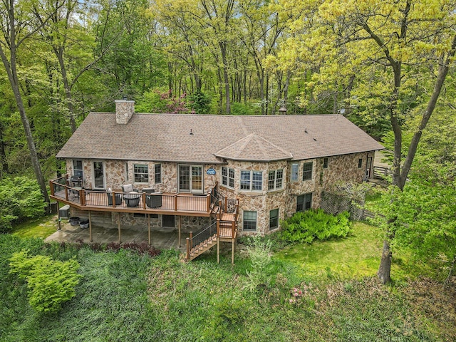 14965 Loon Lake Dr, Bellevue, MI 49021 - rear view of property featuring stone siding, a chimney, a wooden deck, stairs, and a forest view