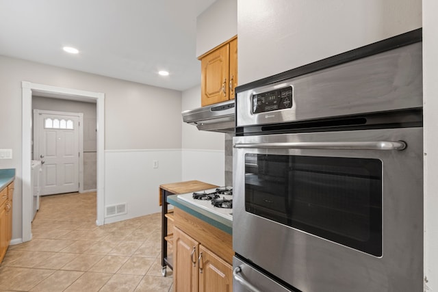 kitchen featuring under cabinet range hood, light tile patterned floors, light countertops, washer / clothes dryer, and recessed lighting