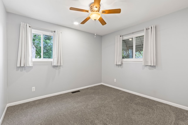 carpeted spare room featuring baseboards and a ceiling fan