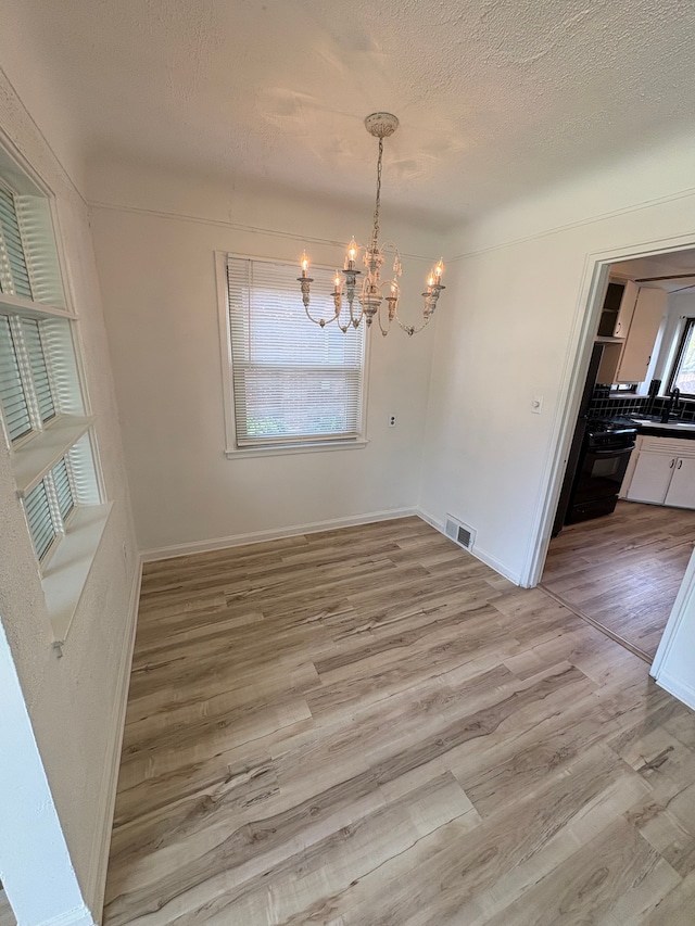 9988 Stout St, Detroit, MI 48228 - unfurnished dining area featuring a chandelier, light wood finished floors, baseboards, and a textured ceiling