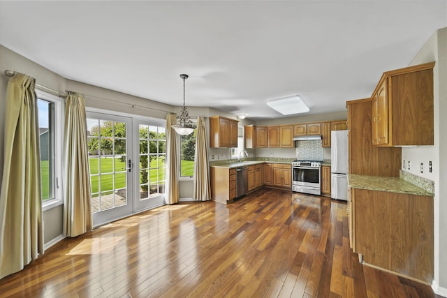 1287 Deer Run, Grass Lake, MI 49240 - kitchen featuring appliances with stainless steel finishes, brown cabinets, dark wood-style flooring, under cabinet range hood, and decorative light fixtures