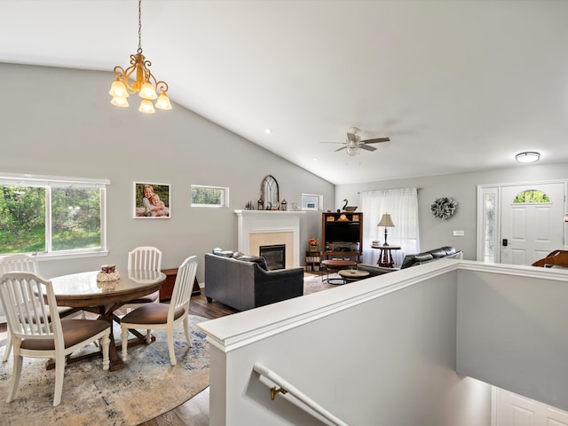 living area with a fireplace, wood finished floors, lofted ceiling, a ceiling fan, and a chandelier