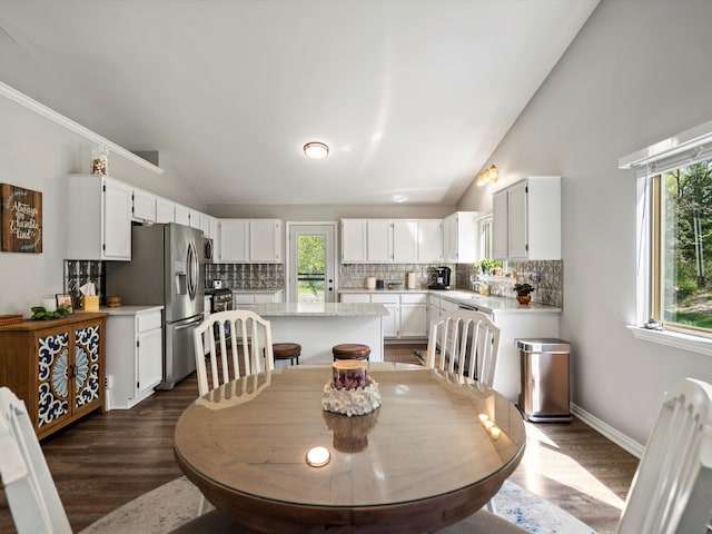 dining room featuring vaulted ceiling, dark wood-style flooring, and baseboards