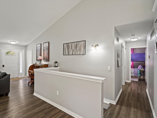 corridor featuring dark wood-style floors, vaulted ceiling, and baseboards