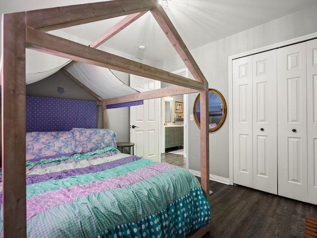 bedroom featuring a closet, wood finished floors, vaulted ceiling, wallpapered walls, and baseboards