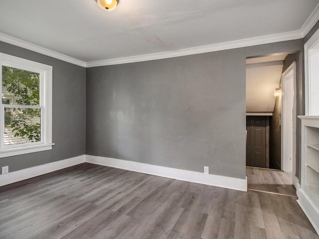 unfurnished room with wood finished floors, crown molding, and baseboards