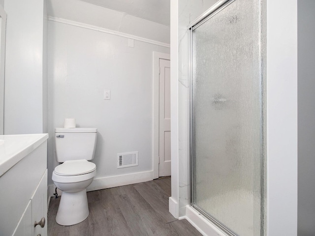 bathroom with wood finished floors, a shower stall, baseboards, toilet, and vanity