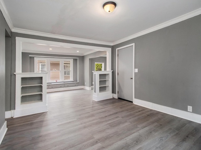 unfurnished living room with ornamental molding, baseboards, and wood finished floors