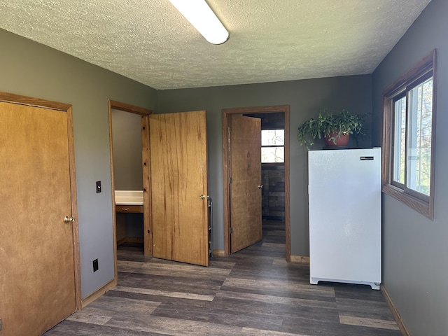 5342 E Fountain Rd, Fountain, MI 49410 - unfurnished bedroom with freestanding refrigerator, a textured ceiling, multiple windows, wood finished floors, and ensuite bath