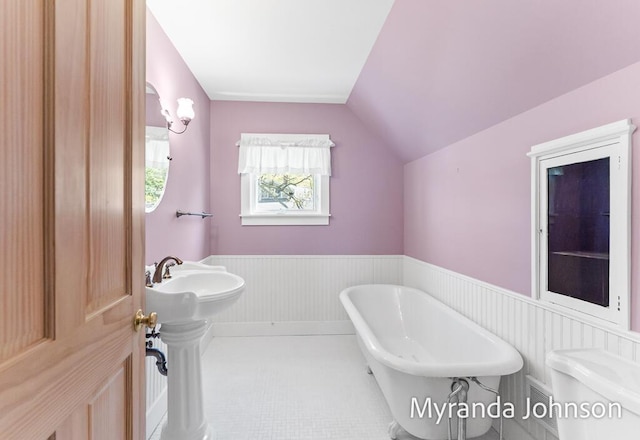 15926 Beach Dr, Spring Lake, MI 49456 - bathroom featuring wainscoting, a freestanding bath, lofted ceiling, toilet, and a sink