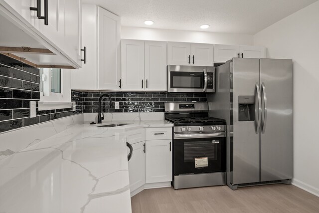 3884 Cass Elizabeth Rd, Waterford, MI 48328 - kitchen featuring stainless steel appliances, light stone countertops, white cabinetry, backsplash, and light wood-type flooring