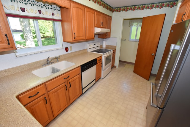 11365 Runnells Dr, Clio, MI 48420 - kitchen with white appliances, a sink, under cabinet range hood, light flooring, and plenty of natural light