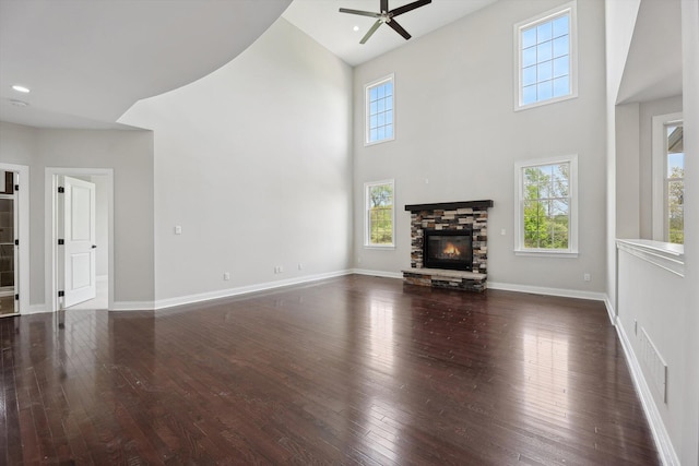 1840 Tapadera Dr, Ann Arbor, MI 48103 - unfurnished living room featuring a towering ceiling, a ceiling fan, hardwood / wood-style flooring, a stone fireplace, and baseboards
