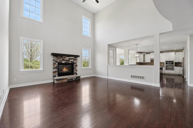 1840 Tapadera Dr, Ann Arbor, MI 48103 - unfurnished living room with healthy amount of natural light, dark wood finished floors, a fireplace, a towering ceiling, and a ceiling fan