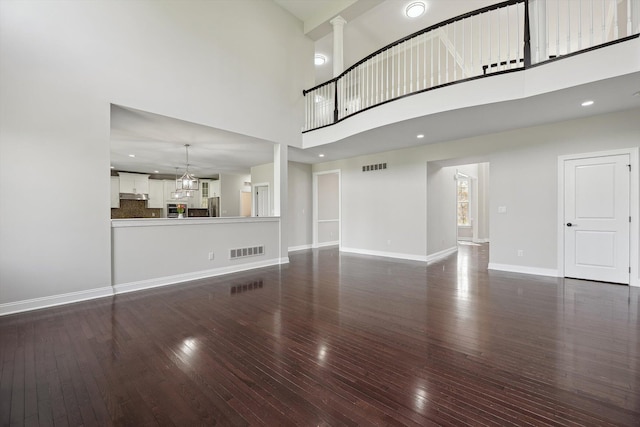 1840 Tapadera Dr, Ann Arbor, MI 48103 - unfurnished living room featuring a towering ceiling, dark wood-type flooring, and baseboards
