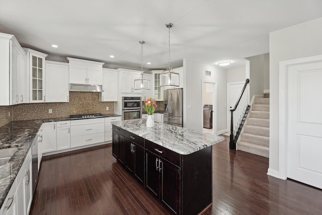 1840 Tapadera Dr, Ann Arbor, MI 48103 - kitchen with stainless steel appliances, under cabinet range hood, washer / dryer, tasteful backsplash, and dark wood finished floors