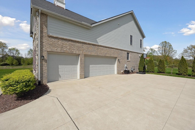 1840 Tapadera Dr, Ann Arbor, MI 48103 - view of side of property with driveway, a garage, brick siding, and a chimney