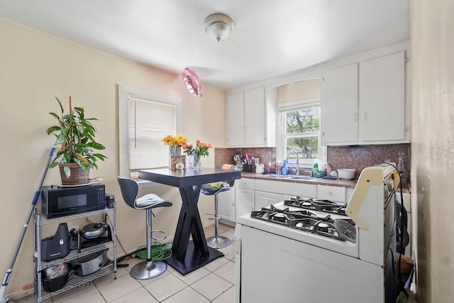 19433 Fenmore St, Detroit, MI 48235 - kitchen featuring a sink, black microwave, white gas range oven, backsplash, and light tile patterned floors