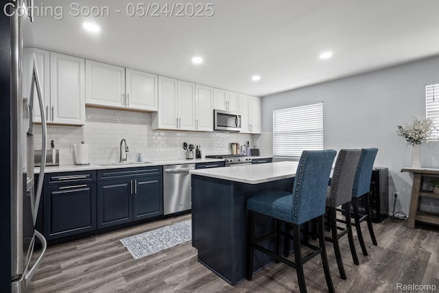 508 Chamberlain St Unit 8, Flushing, MI 48433 - kitchen featuring appliances with stainless steel finishes, a sink, blue cabinets, a breakfast bar area, and decorative backsplash
