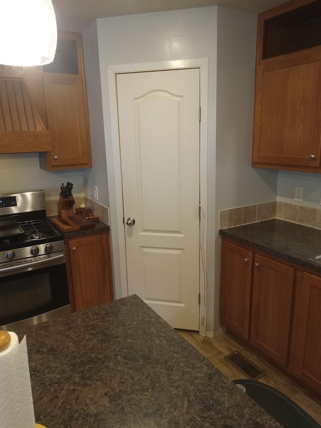 kitchen featuring gas stove, range hood, and brown cabinets