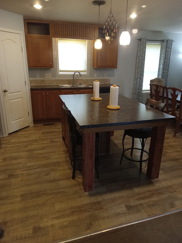 kitchen with a sink, dark countertops, healthy amount of natural light, dark wood-style flooring, and recessed lighting