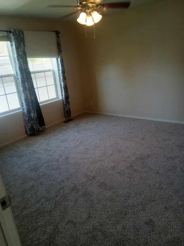 carpeted spare room featuring ceiling fan and baseboards