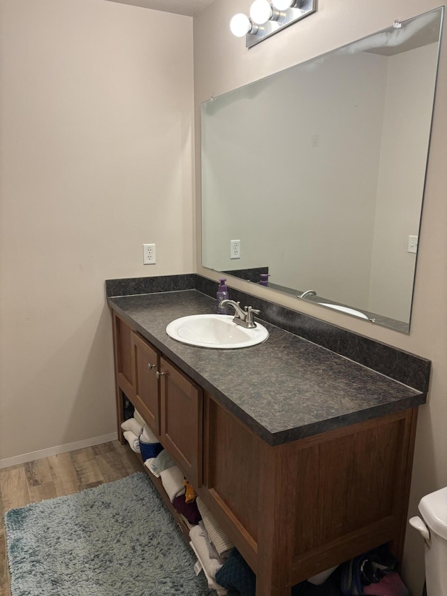 bathroom with wood finished floors, vanity, toilet, and baseboards