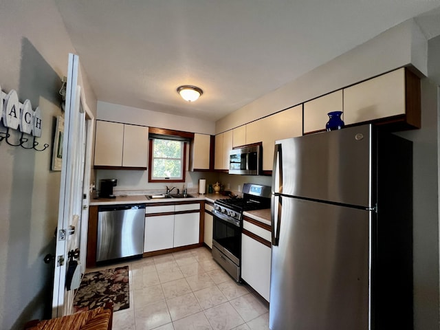 304 S Ferry St Unit 7, Ludington, MI 49431 - kitchen featuring stainless steel appliances, a sink, white cabinetry, light tile patterned floors, and light countertops