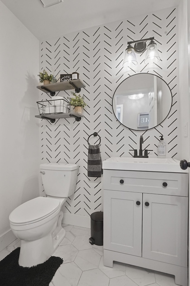bathroom with toilet, baseboards, and vanity
