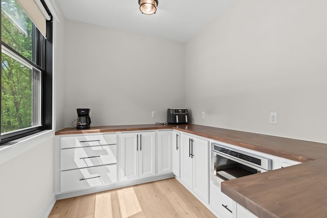 kitchen with butcher block countertops, white cabinets, and light wood-type flooring