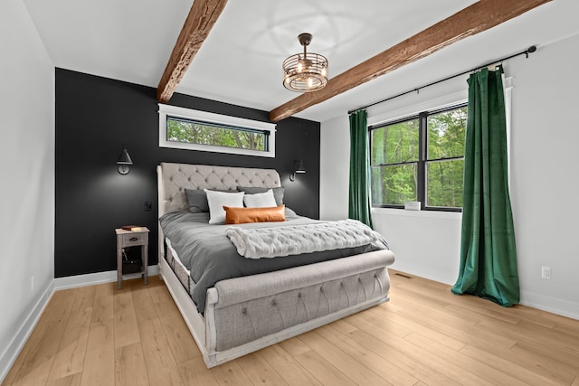 bedroom with beam ceiling, multiple windows, baseboards, and light wood-style floors