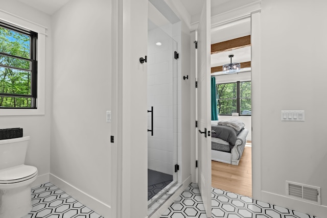 full bath with a stall shower, toilet, ensuite bathroom, baseboards, and tile patterned floors