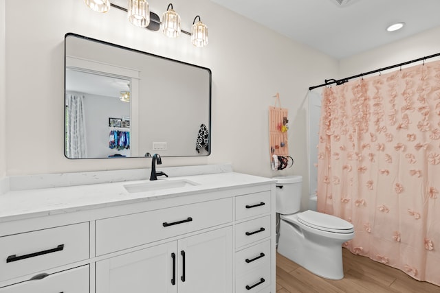 full bathroom featuring wood finished floors, vanity, toilet, and shower / bathtub combination with curtain