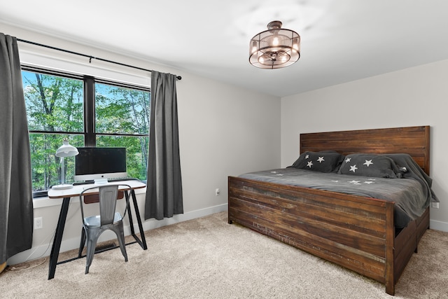 carpeted bedroom with baseboards and a chandelier