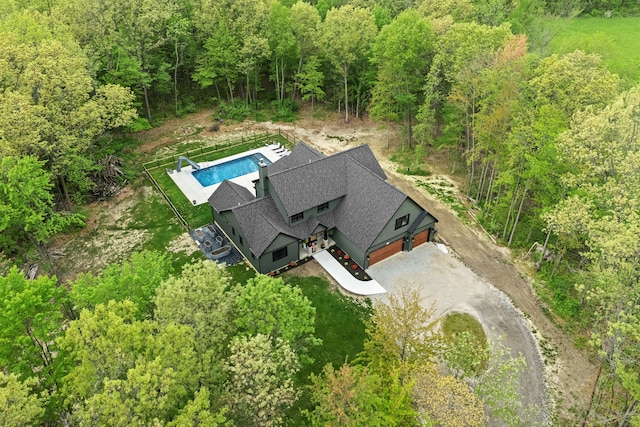aerial view of property and surrounding area featuring a forest and a pool