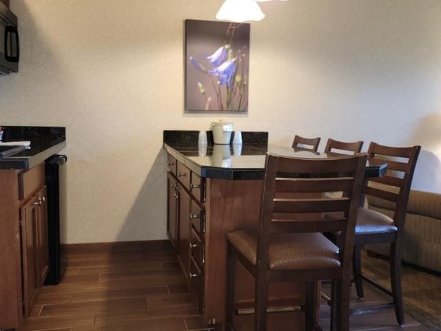 2400 Troon S, Bellaire, MI 49615 - bar with dark wood-type flooring, black microwave, and baseboards