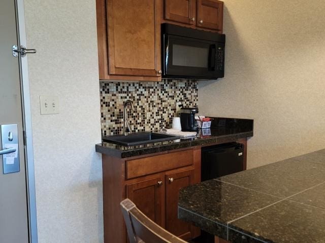 2400 Troon S, Bellaire, MI 49615 - kitchen with black microwave, a sink, backsplash, and brown cabinets