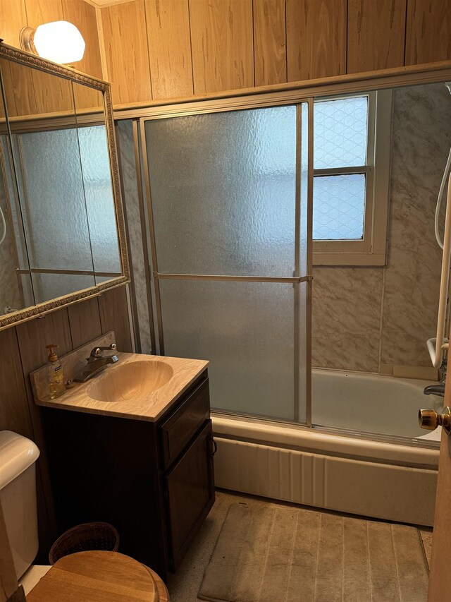 6126 Loud Dr, Oscoda, MI 48750 - full bathroom featuring bath / shower combo with glass door, toilet, vanity, and wooden walls