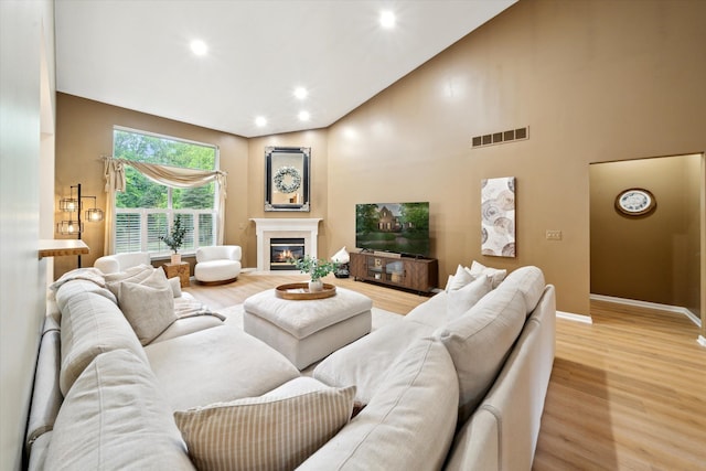 42259 White Hart Blvd, Canton, MI 48188 - living room with light wood-style floors, a glass covered fireplace, baseboards, recessed lighting, and high vaulted ceiling
