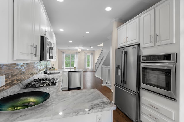 kitchen featuring appliances with stainless steel finishes, a sink, white cabinets, recessed lighting, and dark wood finished floors