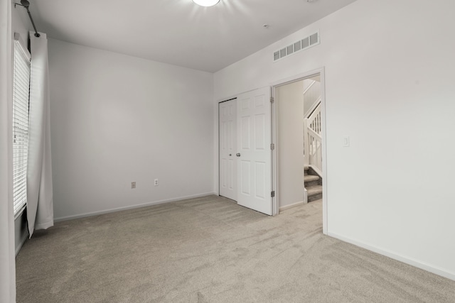 unfurnished bedroom featuring light carpet, baseboards, and a closet