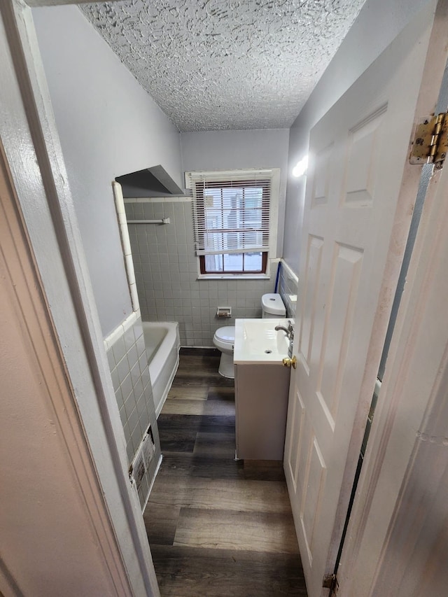 8428 Rosemont Ave, Detroit, MI 48228 - bathroom with tile walls, toilet, wood finished floors, vanity, and bathtub / shower combination