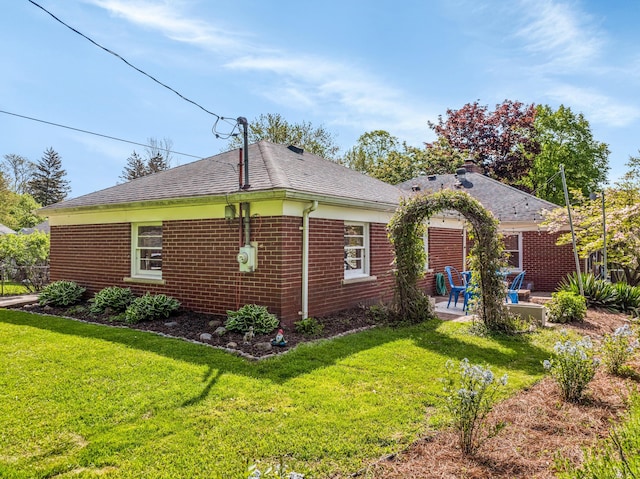 212 W Mckay St, Saline, MI 48176 - view of side of property featuring a patio, a lawn, brick siding, and a shingled roof