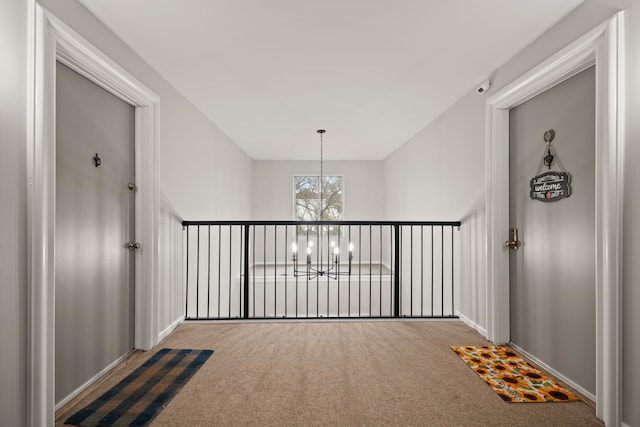 hallway with a chandelier, carpet, and baseboards